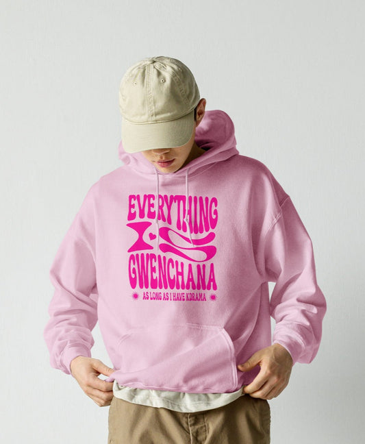 Person wearing a pink hoodie with text, Everything is Gwenchana Hoodie ARCHVSTS™ beige cap, and brown cargo pants on a plain background