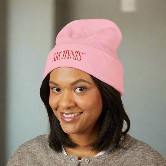 Person wearing a pink beanie with 'ARCHVSTS' logo on a white background