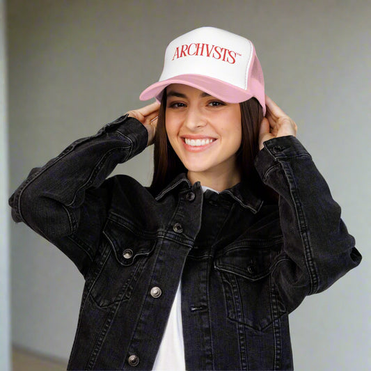 Person wearing a pink cap with 'ARCHIVIST' logo and black denim jacket on a white background