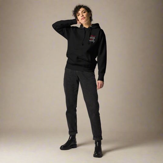 Person wearing a black hoodie and pants on a beige background