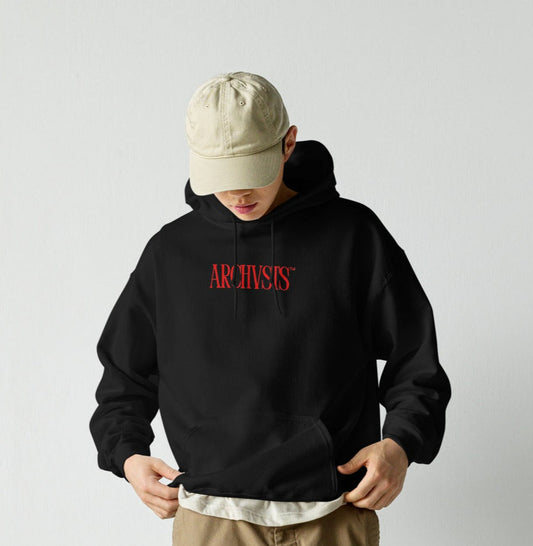 Person wearing a black ARCHVSTS™ HOODIE with a beige cap, and brown cargo pants against a white background