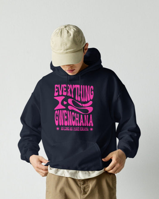 Person wearing a navy hoodie with pink text everything is gwenchana, beige cap, and brown cargo pants against a white background