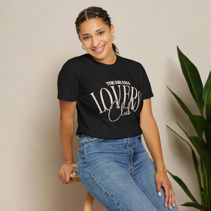 Person wearing a black t-shirt with 'The Drama Lovers Club' text and blue jeans on a white background