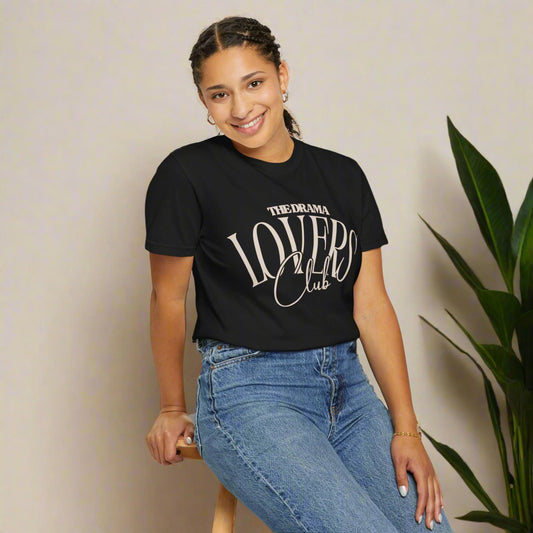 Person wearing a black t-shirt with 'The Drama Lovers Club' text and blue jeans on a white background