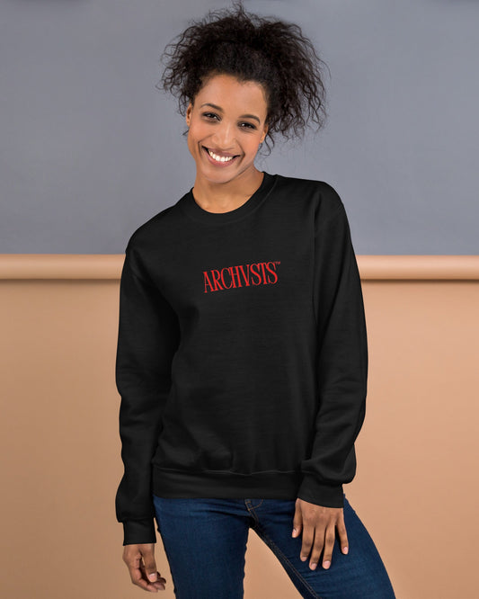 Person wearing a black sweatshirt with 'ARCHIVISTS' in red text on the front against a beige and gray background