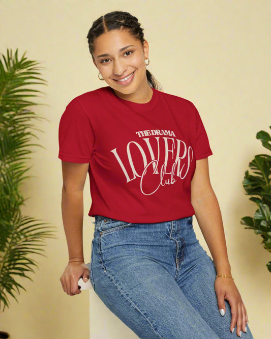 Person wearing a red 'The Drama Lovers Club' t-shirt and blue jeans on a white background